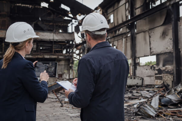 Експерти в захисних касках оглядають пошкоджену промислову будівлю та фіксують наслідки руйнувань